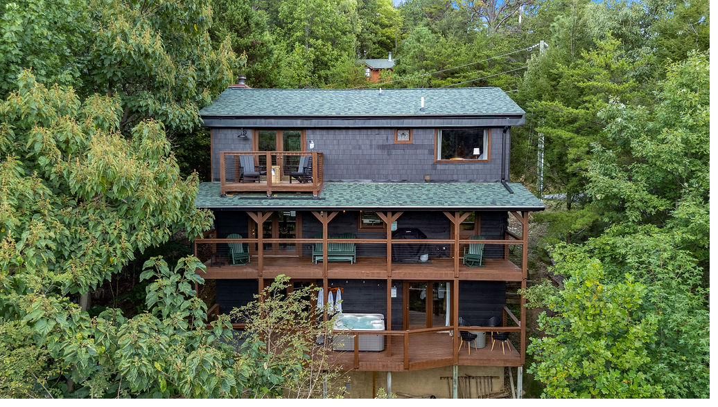 Aerial view of The Smoky Edit log cabin and its three stacked decks among the trees in Cobbly Nob